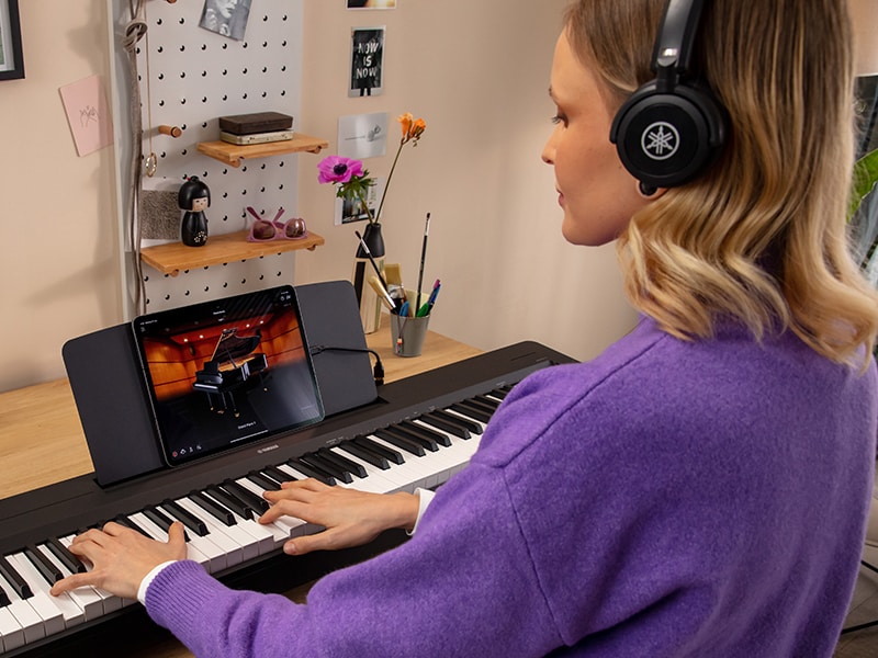 A person using headphones while practicing on the P-145BT
