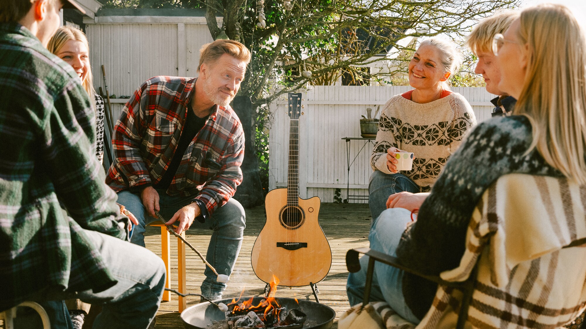Group of friends outdoors with the TAG3 C acoustic guitar beside them.
