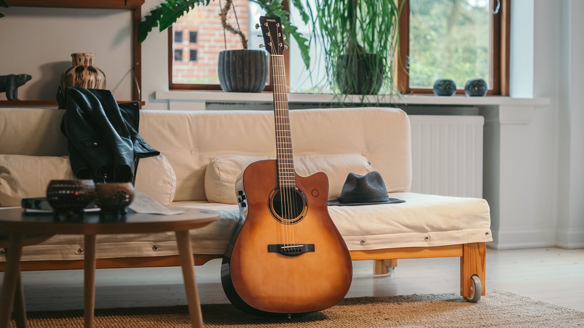 TAG3 C acoustic guitar placed on a sofa with a bag beside it.
